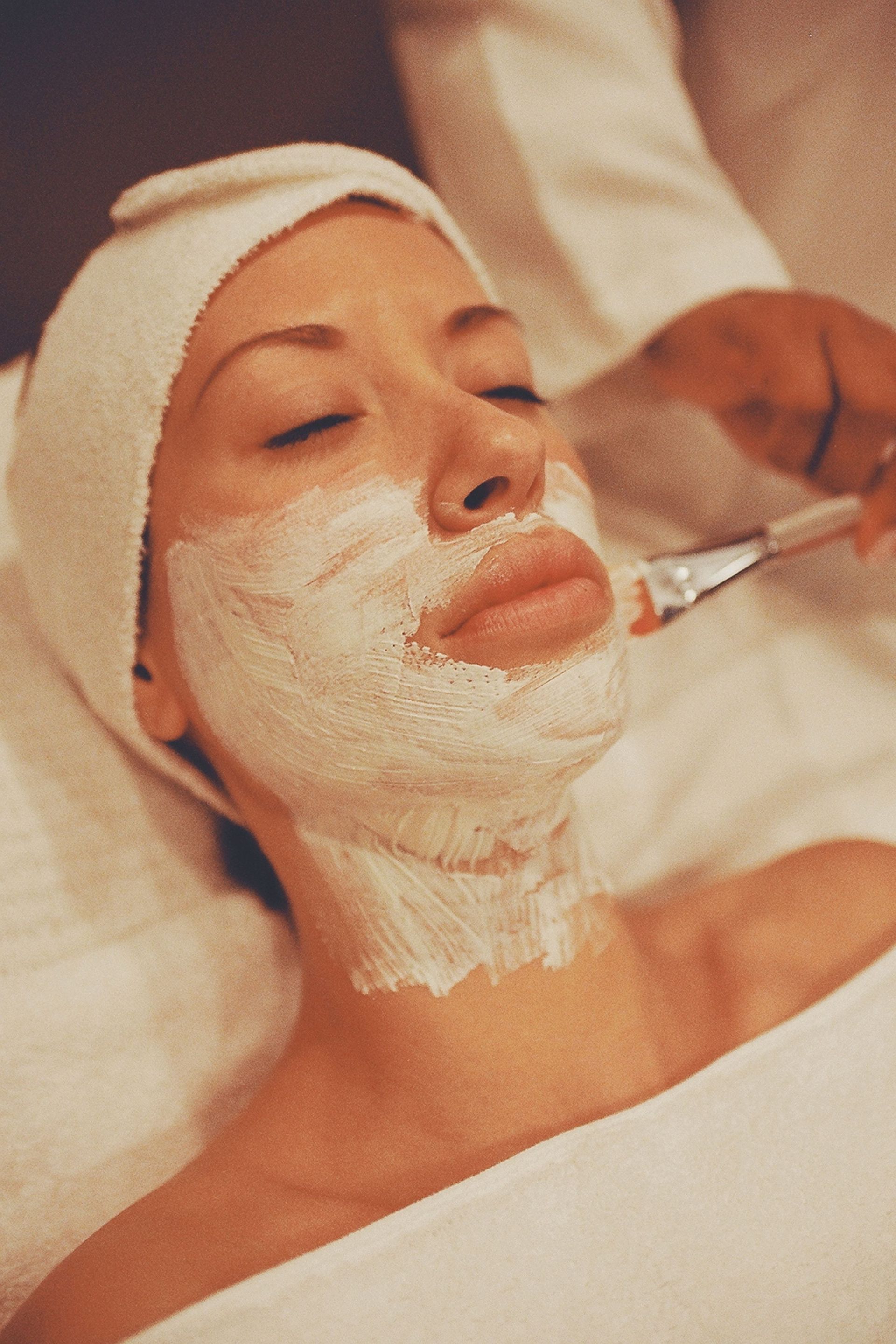 Close-up of a woman receiving a soothing facial mask at a spa, promoting relaxation and skincare.
